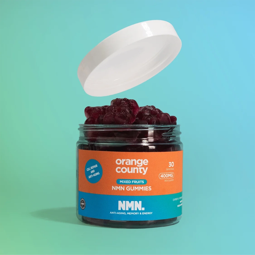 A jar of Orange County NMN Gummies with its white lid propped open, showing dark red gummies inside. The jar features a bright orange and blue label with white text.