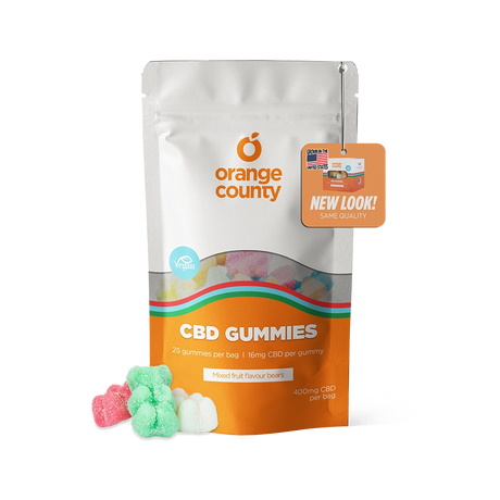 An orange and white stand-up pouch of Orange County CBD Gummies with a clear window showing multicolored gummies inside, plus three loose gummies in front on a white background.
