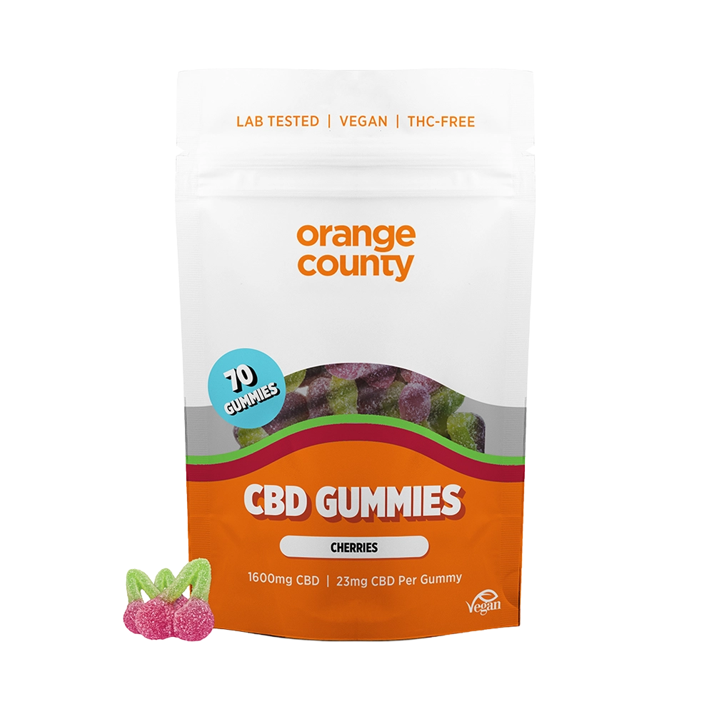 An orange and white stand-up pouch of Orange County CBD Gummies (Cherries) on a white background, with three cherry-shaped gummy candies displayed in the lower-left corner.