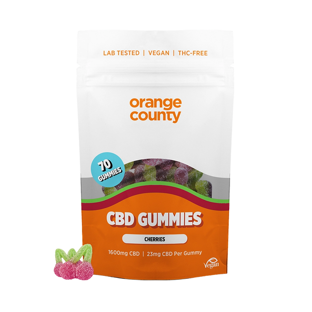 An orange and white stand-up pouch of Orange County CBD Gummies (Cherries) on a white background, with three cherry-shaped gummy candies displayed in the lower-left corner.