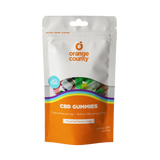 A stand-up pouch of Orange County CBD Gummies on a plain white background. The packaging is white on the top half with an orange logo and a clear window showing multicolored gummies, and orange on the bottom half with rainbow accents and product text.