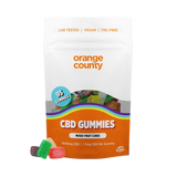 A stand-up pouch of Orange County CBD Gummies on a plain white background, with a few gummy candies placed in front. The package is mostly white and orange with a clear window showing multicolored gummies inside and a blue circular badge that says 95 gummies.