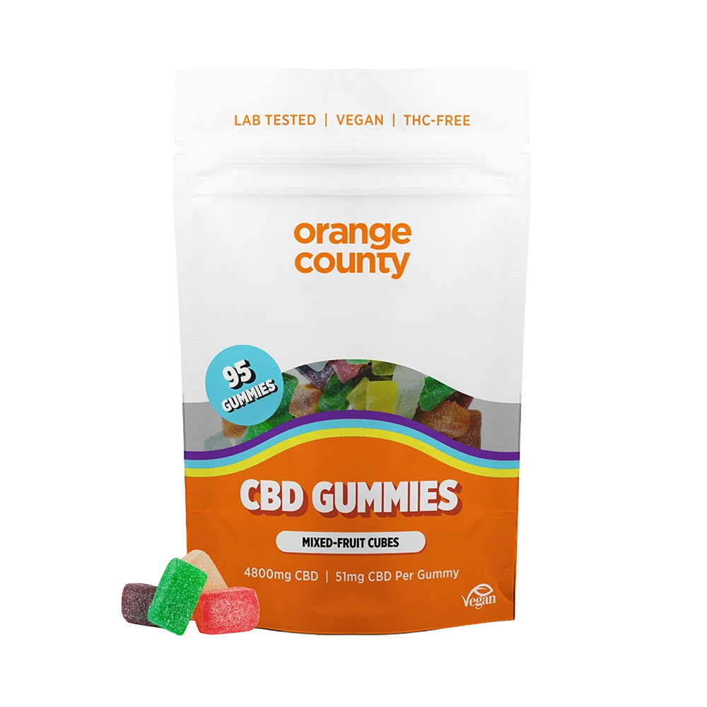 A stand-up pouch of Orange County CBD Gummies on a plain white background, with a few loose gummy candies placed in front. The package is mostly white and orange with a clear window showing multicolored gummies inside and a blue circular badge that says 95 gummies.