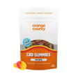 An orange and white stand-up pouch of Orange County CBD Gummies, labeled 'Peach Rings', with two gummy candies placed in front on a white background.