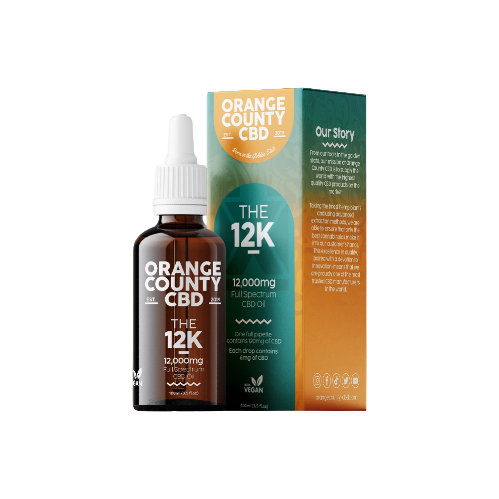An amber glass dropper bottle of Orange County CBD 'The 12K' 12,000mg Full Spectrum CBD oil stands next to its matching cardboard packaging box on a clean white background.