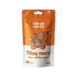 A 225g stand-up pouch of Natural Calming Treats for dogs by Orange County, featuring an orange and white design with a paw print window showing the treats inside.