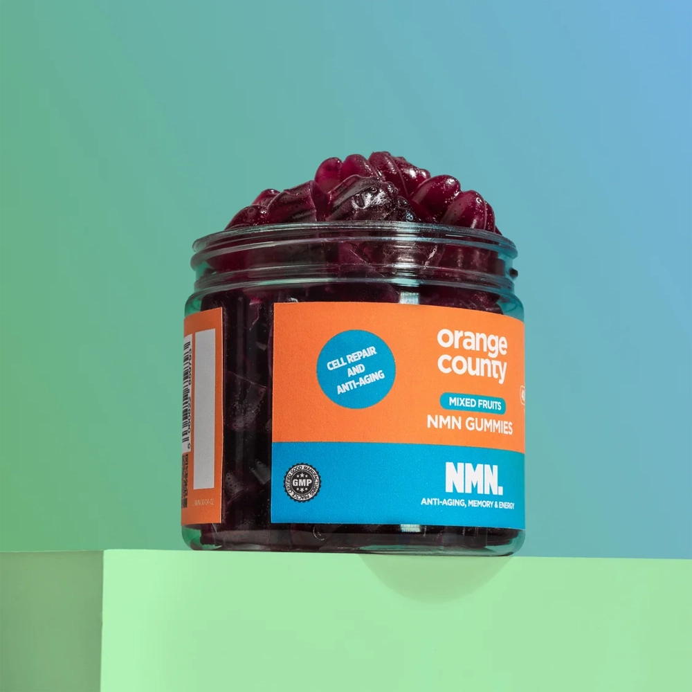 A clear jar of Orange County NMN Gummies filled with dark red gummies, set on a light green pedestal against a teal-to-blue gradient background.