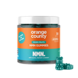 A jar of Orange County NMN Gummies for mixed fruits, featuring a bright orange and teal label with a white lid, shown alongside three green gummy bear candies on a white background.