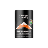 A black cylindrical container of Orange County Himalayan Shilajit Pure Shilajit Resin, featuring an orange and white mountain graphic on the label, set against a plain white background.
