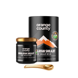 Orange County Himalayan Shilajit Pure Shilajit Resin shown with a black cylindrical container, a small black jar with a gold lid, and a gold spoon on a white background.